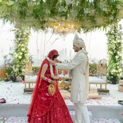 The Varmala ceremony under a canopy of lush greenery and elegant chandeliers. We focus on creating a serene and beautiful atmosphere for this sacred exchange.