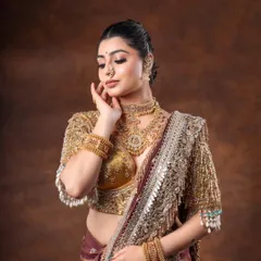 A moment of grace in a traditional bridal look. The model's soft expression and the rich gold jewelry create a timeless and beautiful portrait.