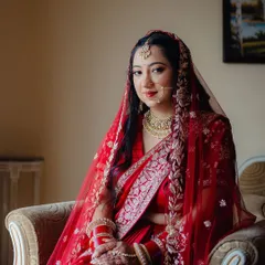 A portrait of a beautiful bride in a traditional red saree for her North Indian wedding. The look is completed with a delicate nath and a soft glam makeup look that enhances her features.