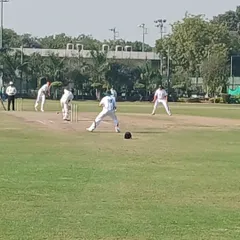 Action from the pitch during a match, showing our batsman ready to face the bowler with fielders in position. This real-match scenario is essential for developing game awareness.