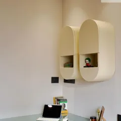 Detail of the pill-shaped wall cabinets. Their rounded form adds a soft, modern touch, and the open niche is perfect for displaying small, personal items, making the workspace feel more personalized.
