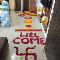 A beautiful 'WELCOME' message and swastika symbol created with red and yellow flower petals for a baby's homecoming ceremony.