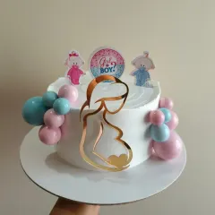 A sweet gender reveal cake with a "Girl or Boy?" topper and an acrylic silhouette of an expecting mother.