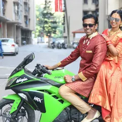 A modern and stylish post-wedding shot of the newly married couple on a green Kawasaki Ninja motorcycle.