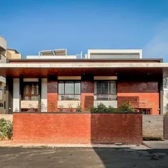 A frontal view of the Hennur residence, highlighting the use of a low brick wall for privacy while maintaining a connection to the streetscape.