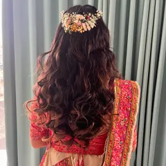 A crown of flowers for a beautiful bride. This hairstyle features soft curls and a half-up style, adorned with a fresh floral hairpiece for a romantic and natural look.