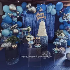 A sophisticated birthday setup in shades of royal blue and silver. The decor features a tiered cake, an elegant dessert display on acrylic stands, and a shimmering blue backdrop, creating a luxurious and cool-toned vibe.