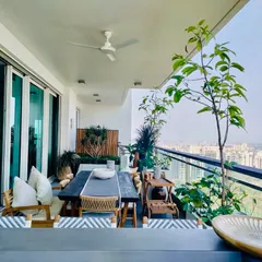 A well planned garden is a room outside your home. This balcony is a perfect combination of aesthetics, greenery, and utility, with a large dining table, comfortable chairs, and a variety of potted plants.