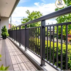 A long expanse of modern black railing secures a spacious terrace with a wooden deck. The simple vertical design ensures safety without obstructing the view of the lush green surroundings, making it perfect for enjoying the outdoors.