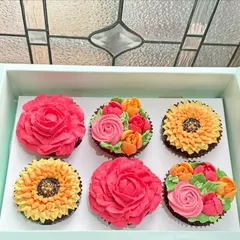 A beautiful box of six hand-piped floral cupcakes ready to make someone's day. This set features a mix of vibrant buttercream roses and sunflowers on our classic chocolate cupcakes, perfect for birthdays, thank you gifts, or just because.