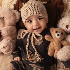 Can you spot the cutest teddy bear in this pile? This little one, with his adorable knit hat, is surrounded by furry friends in a cozy and classic sitter session setup.