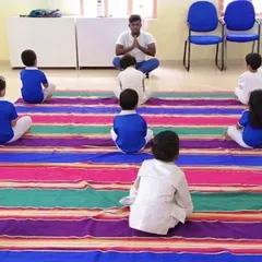 A peaceful moment as children sit in a circle for a guided yoga and meditation exercise. These practices help enhance happiness and strength from within, providing tools for focus and calm.