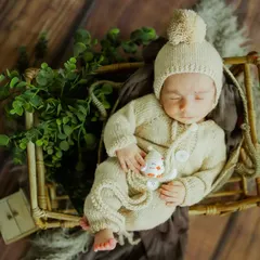 Dreaming of big adventures. This little one is snug and warm in his knitted romper, a timeless and cozy look for a newborn session. The rustic props add a natural touch.