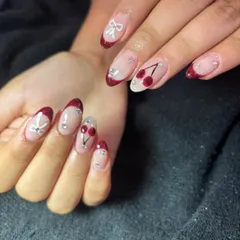 A cute and playful French manicure with a deep red, glittery tip. The design is accented with hand-painted cherries and tiny white bows for a sweet, detailed look.