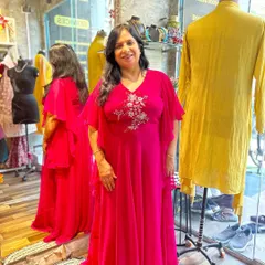 A client looking radiant in a custom-embroidered fuchsia gown with graceful ruffled sleeves. I designed this piece to be both comfortable and glamorous for any festive gathering.
