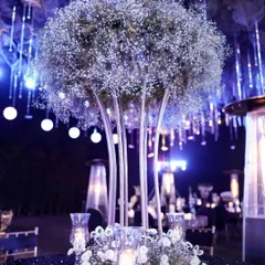 A stunning centerpiece for a luxury cocktail event, featuring a large globe of baby's breath flowers, set against a backdrop of hanging lights.