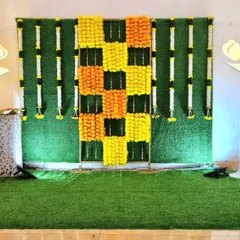 A traditional backdrop setup with a marigold checkerboard pattern on a grass wall, ready for seating to be added.