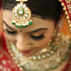 A detailed close-up of the bride's maang tikka and shimmering eyeshadow. We pay close attention to the artistry of bridal makeup and jewelry in our portrait photography.