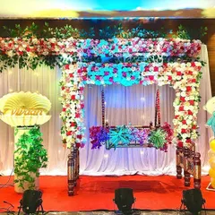 A complete stage for a Namkaran Sohala. The setup includes a decorated cradle, cute baby cutouts, and the special seashell prop on a pedestal, ready for the big name reveal moment.