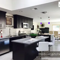 A classic dark-themed modular kitchen with an island counter. This design provides ample storage and workspace, seamlessly integrating with the open-plan living area.