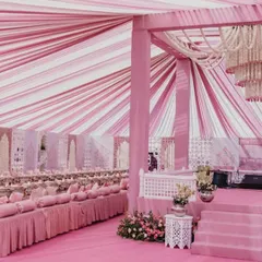 We transformed this space into a pink paradise with floor-to-ceiling decor. The striped pink and white fabric ceiling, mirrored jaali panels, and plush low seating create a regal and cohesive look for a grand celebration.