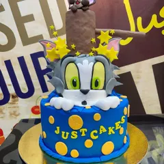 The ultimate cartoon chase comes to life on this 6kg Tom & Jerry cake. It features a large, sculpted Tom head with Jerry popping out of a log on top, all crafted with detailed fondant work.