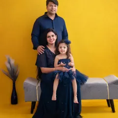 A formal family portrait using a bold, solid-colored backdrop. The coordinated navy blue outfits create a cohesive and polished look, making this a timeless keepsake.