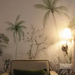 A closer look at the 'Whispering Willow' wallpaper, where the warm glow of a wall lamp highlights the delicate details and soft colors of the trees and birds.
