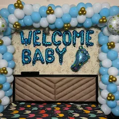 Another style for a bedroom welcome decoration. This setup features a full balloon frame around the headboard in blue, white, and gold, with "WELCOME BABY" foil balloons in the center.