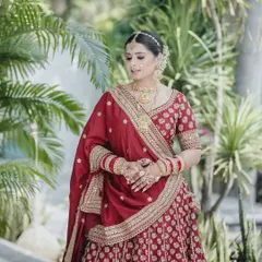 A full-length shot of the bride in her stunning red lehenga, set against a lush green background that makes her colors pop.