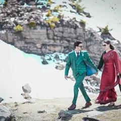 A candid shot of a couple walking hand-in-hand through a rocky, snow-dusted landscape in Manali. This showcases a blend of high-fashion styling with the raw beauty of the Himalayas.