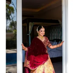 A beautiful bride in a rich velvet lehenga, ready for her Jaipur destination wedding. This shot captures her looking out of her palace hotel room, full of grace.
