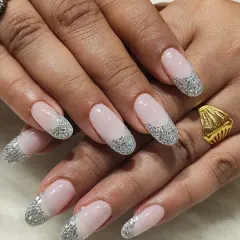 Glamour meets classic in this glittery French tip design. The long, oval nails have a sheer pink base and tips packed with sparkling silver glitter, perfect for any party or special occasion.