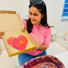 A participant smiles, delighted with the heart-shaped fluid art piece she just created. The process is all about letting go and trusting the flow.