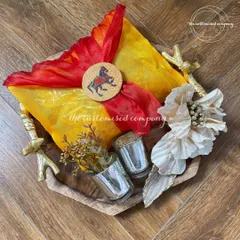 I designed this unique Diwali hamper on a beautiful wooden tray with ornate metal handles. It features shot glasses for serving and a colorful bandhani-wrapped gift, blending rustic charm with festive tradition.