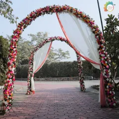 A grand entrance composed of two massive floral arches, draped with soft, flowing fabric. This creates a spectacular and romantic gateway for any wedding celebration.