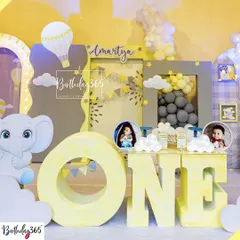 A close-up of a charming hot air balloon and elephant themed first birthday. This shot highlights the large 'ONE' letters for photo opportunities and the custom-designed backdrop with cute illustrations and balloon clouds.