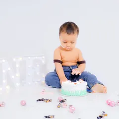 The moment before the fun begins. A portrait of the birthday boy with his first cake and the 'ONE' light-up prop in the background.