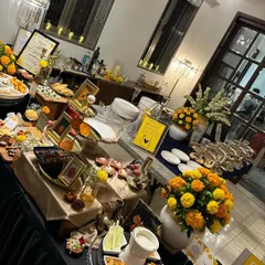 A vibrant and festive buffet spread decorated with marigolds for a special occasion. The setup includes a mix of cheese boards, appetizers, and main courses, creating an inviting and celebratory atmosphere for guests.
