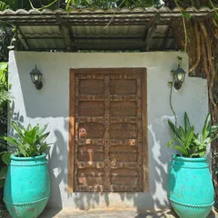 Make an entrance that tells a story. Our antique-finish terracotta 'Ubud' planters add a vibrant pop of turquoise, beautifully framing this rustic wooden door and creating an unforgettable welcome.