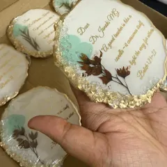 Holding one of the finished coasters. The combination of the white base, gold edge, and preserved flowers gives it a very elegant look.