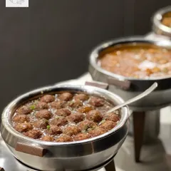 A tempting view of our main course offerings. Here, a chafing dish is filled with delicious Manchurian balls in gravy, kept warm and ready for guests to enjoy at their leisure.
