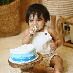 A cute moment from a cake smash photoshoot, with the baby boy enjoying a taste of the icing. The focus is on his happy and natural expression.