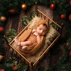 A sleeping newborn nestled in a tiny bed, surrounded by a festive wreath of pine and ornaments. This artistic shot is a beautiful way to celebrate your baby's first Christmas.