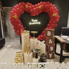 Make a bold statement with a custom heart-shaped balloon arch. This dramatic red balloon heart, paired with a glowing 'Happy Anniversary' neon sign and personalized light-up names, creates a stunning focal point for your celebration.