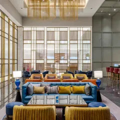 The vibrant lounge at Holiday Inn, Lucknow, showcasing a dynamic interplay of color and texture. We designed this public space with varied seating arrangements, from plush blue sofas to mustard yellow armchairs, to foster social interaction while intricate metal screens provide a sense of privacy.