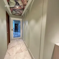 Looking down the hallway, you can see how the arched wall moldings echo the shape of the doorway, creating a sense of rhythm and flow. The marble flooring adds a touch of luxury that connects the entire space.