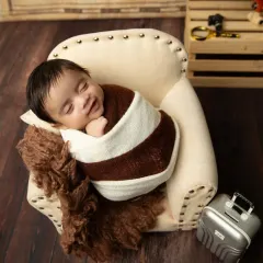 A sleepy smile from our little traveler. Swaddled snugly in a miniature armchair, this baby is all set for a journey in their dreams. The vintage map background adds to the adventure.
