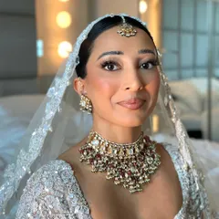 The complete bridal look with the veil placed over the sleek low bun. The simplicity of the hairstyle ensures it doesn't compete with the heavily embellished veil and outfit.
