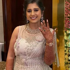 A happy client showing off her beautiful floral mehendi at her engagement party. The design extends up her forearm, complementing her elegant gown.